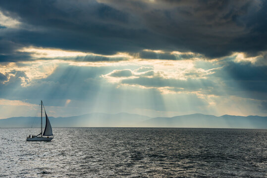 Sailing boat before the sun breaking through the clouds above the Amur in Vladivostok, Russia