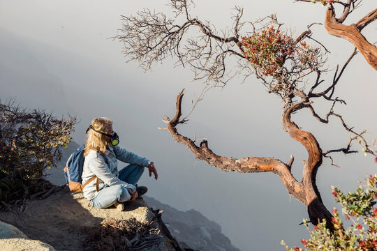 Woman with respirator mask sitting at volcano Ijen, Java, Indonesia