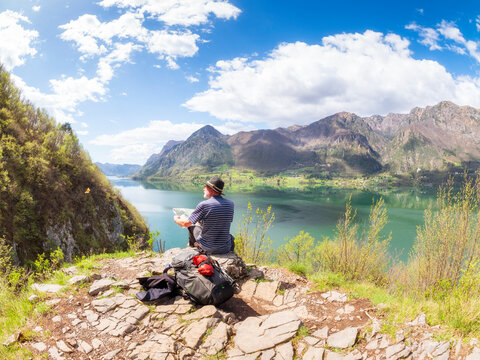 Italy, Lombardy, spring at Lake Idro, hiker sitting with map at observation point
