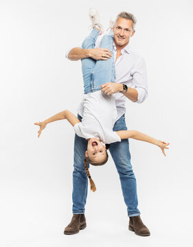 Father carrying daughter upside down while standing against white background