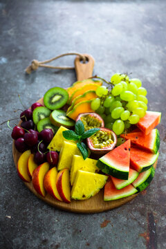 Fruit salad with watermelon, kiwi, passion fruit, grape, cherry, peach and melon on chopping board