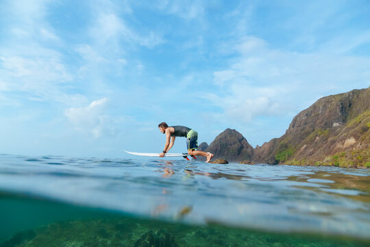 Surfer jumping from stone, Sumbawa island, Indonesia
