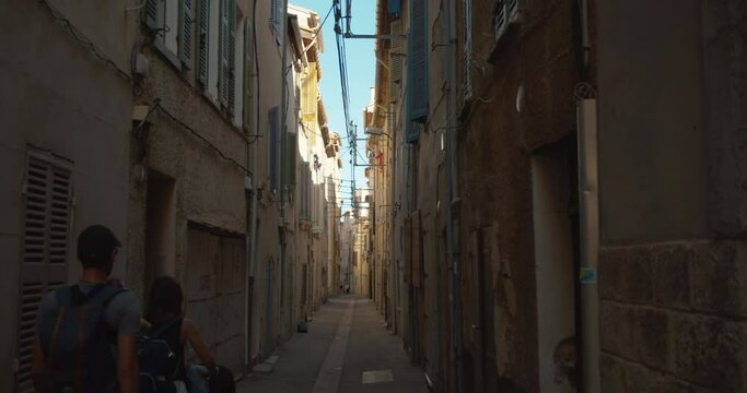 Couple passing by a narrow street. Typical provencal village. Beautiful light fluctuations and shadow