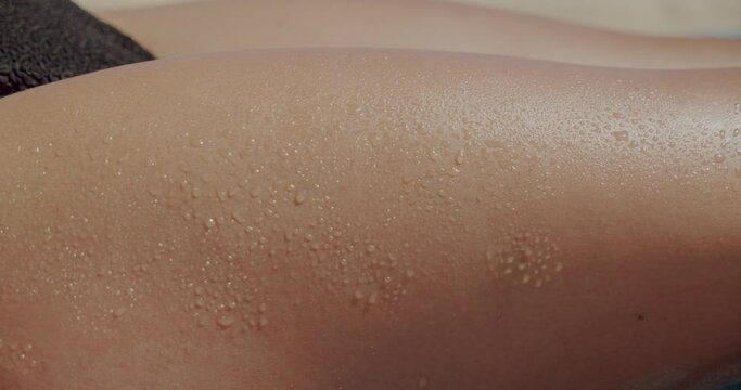 Closeup woman thigh tanning. Caucasian girl leg in the sun with water drops