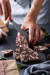 Female hands cutting Traditional Italian dessert - christmas chocolate salami