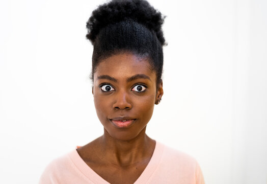 Surprised woman staring while standing against white background