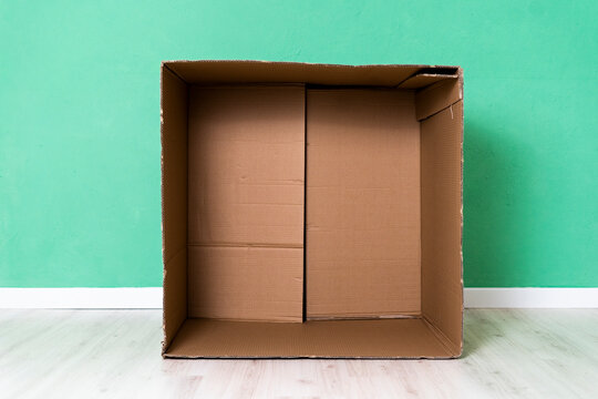 Empty cardboard box against green wall in apartment