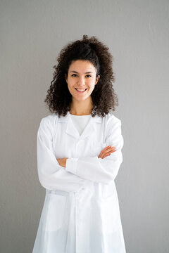 Smiling female doctor with arms crossed against wall at clinic