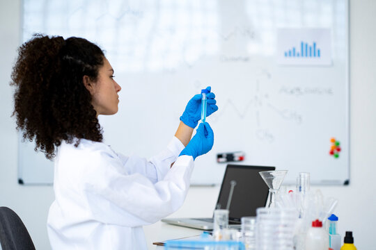 Young female researcher analyzing chemical solution in test tube at clinic