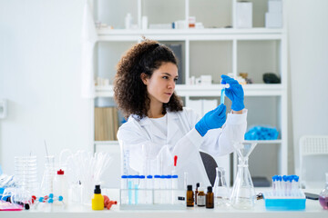 Female scientist analyzing chemical solution in test tube at hospital