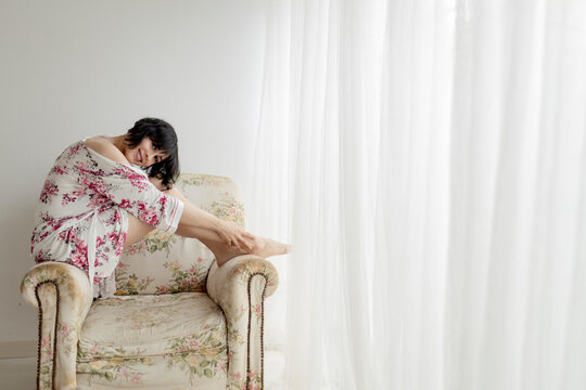 Woman In Nightwear Sitting On Armchair At Home