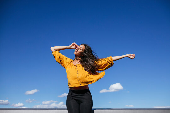 Carefree woman dancing on roof terrace in sunlight