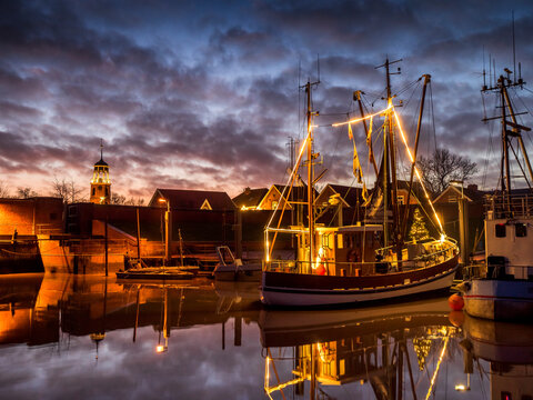 Germany, Lower Saxony, Landkreis Leer, Friesland, Ditzum, Ship illuminated for Christmas at dusk