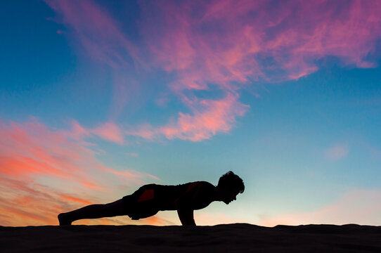 Silhouette of man doing push-ups at sunset, Gran Canaria, Spain