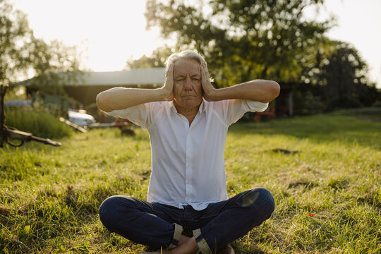 Man practicing yoga while sitting in backyard