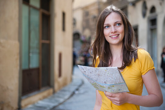 Portrait of smiling woman with city map in an alley, Florence, Italy