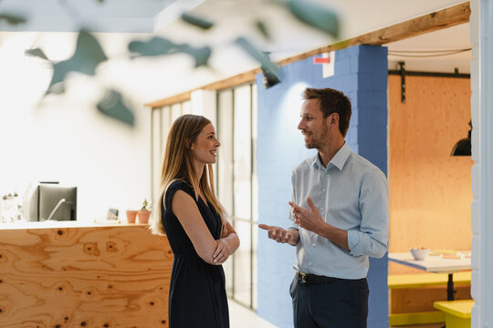 Businessman and businesswoman standing in modern office, discussing