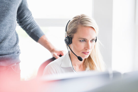 Female customer service representative wearing headset while using computer in office