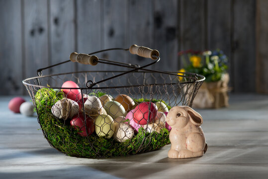 Easter eggs in wire basket with Easter bunny in the foreground