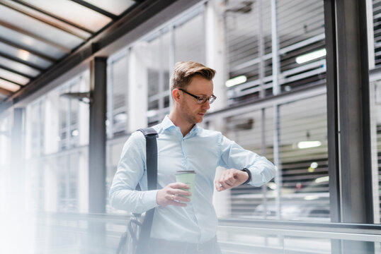 Businessman with coffee checking the time in city