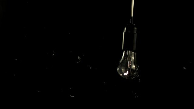 Super slow motion light bulb crashed with shards of glass. On a black background. High quality FullHD footage