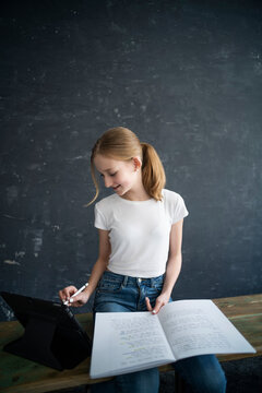 Blond girl learning and using tablet at home