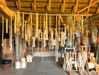 Mooring ropes on a wooden beam in barn hang out to dry in stone shed. Raw materials for the manufacture of ropes.