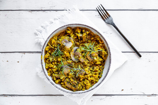 Bowl of yellow and green cauliflowers with fried champignons and rosemary
