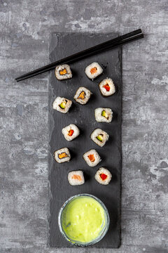 Sushi on slabe plate, wasabi in bowl, chop sticks
