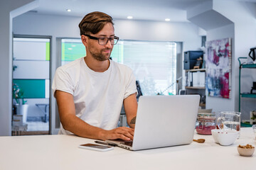 Male student using laptop at kitchen island in cooking class