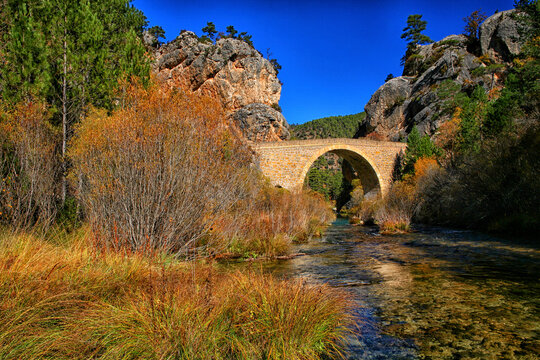 Spain, Province of Guadalajara, Stone arch bridge over river flowing in Alto Tajo Nature Reserve