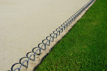 a metal decorative curb in the shape of bent rods, ripples or an endless snake climbing out of the...