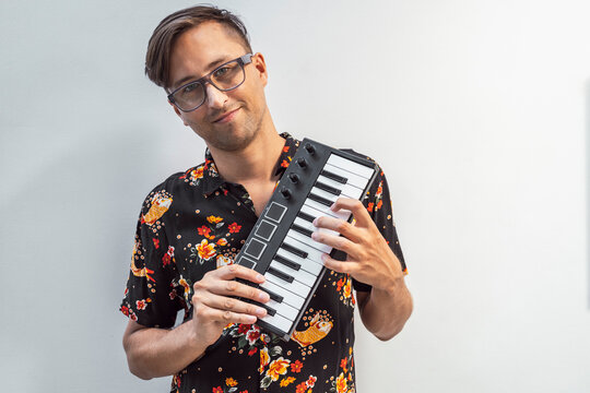 Smiling man holding midi keyboard while standing against wall