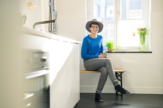Portrait of smiling sitting on bench in kitchen at the window