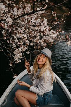 Japan, Tokio, Chidorigafuchi Park, smiling woman in rowing boat at cherry tree blossom