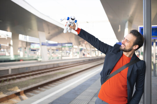 Smiling entrepreneur looking at robot on railroad platform