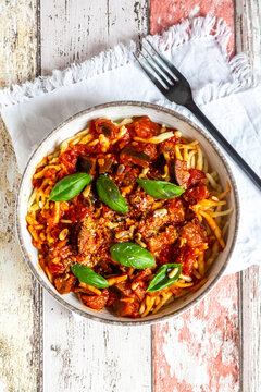 Bowl of pasta with aubergine tomato sugo garnished with pine nuts, parmesan and basil