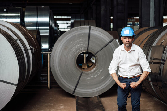 Businessman flexing muscles while standing in factory