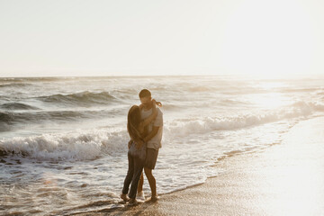 Affectionate young couple hugging at the seashore at sunset