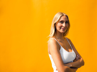 Attractive woman with arms crossed standing against yellow wall