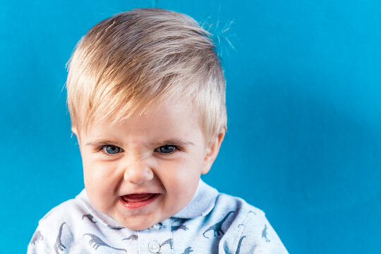 Smiling baby boy standing against blue wall