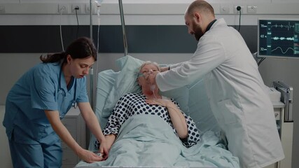 Doctor and nurse helping ill woman breathing heavily, using oxygen mask with tube for respiratory recovery. Medical team giving support to hyperventilating patient in hospital ward.