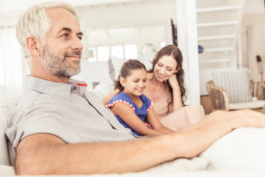 Smiling mature man with family on couch in living room