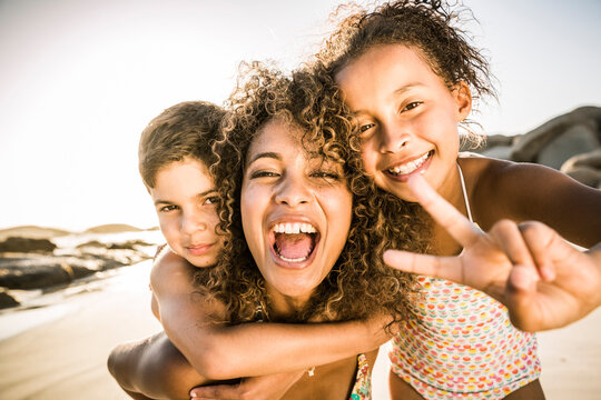 Portrait of a happy mother with her two kids having fun on the beach