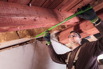 Roof insulation, worker measuring wood fibre insulation