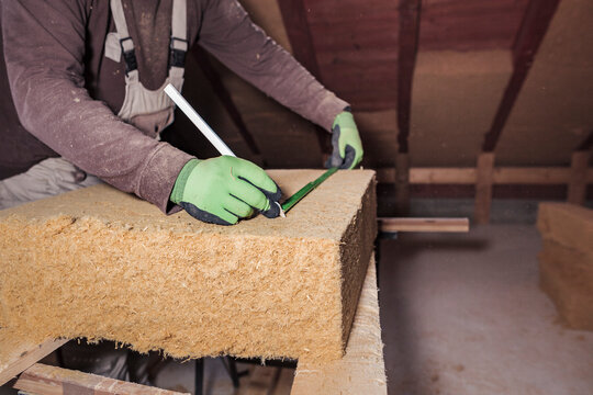 Roof insulation, worker measuring wood fibre insulation