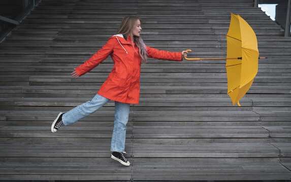 Playful young woman holding umbrella while dancing on steps