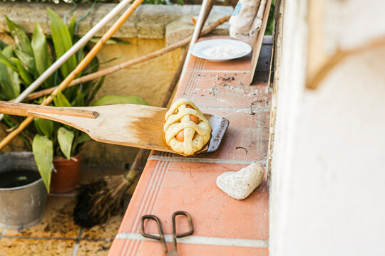 High angle view of Mona De Pascua on pizza peel by wood burning stove