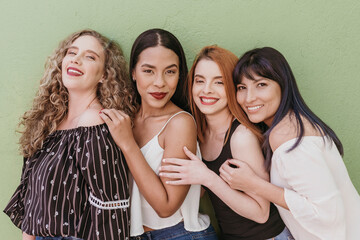 Happy multi ethnic friends standing against green wall