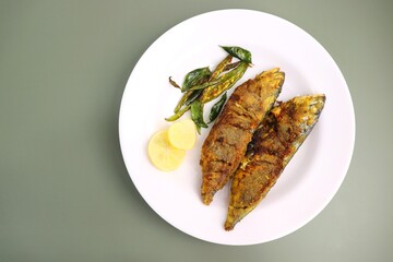 Indian Mackerel fish fry. Bangda Rava fry. whole Fried fish served on a banana leaf with fried chilies, lemon slices, and Indian spices. also known as talalele bangde in Marathi. Copy space.